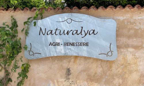 a sign on the side of a wall with vines at Naturalya in Vibonati
