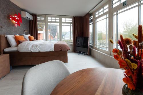 a bedroom with a bed and a tv and a table at B&B Carpe Diem in Westerlo