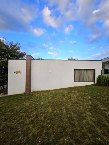 a white building with a door and a grass field at Villa Ipanema in Tʼelavi