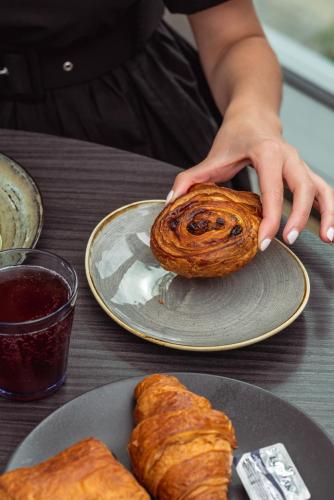 a person holding a pastry on a plate on a table at CitySuites 2 Aparthotel in Manchester