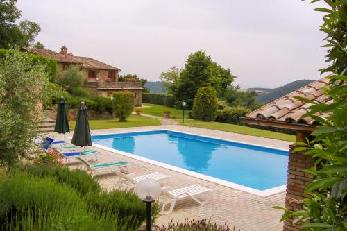 a swimming pool with chairs and umbrellas next to a house at Villa Bea by MMega in Corgna