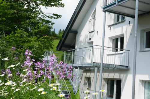 a white building with a balcony and purple flowers at Loft "Island" in Leutkirch im Allgäu