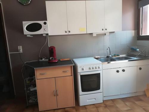 a kitchen with white cabinets and a stove and a sink at Studio le Bastion in Algajola