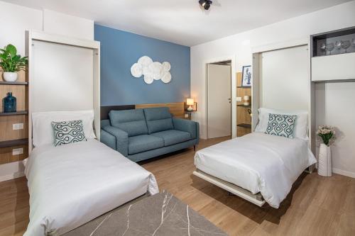 a bedroom with two beds and a blue couch at Brezza Marina Deluxe Apartment in Grado