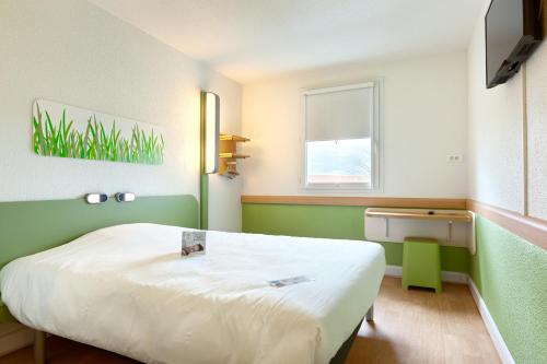 a small room with a bed and a window at ibis budget La Roche Sur Yon Vendespace in Mouilleron-le-Captif