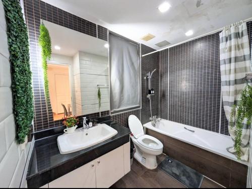 a bathroom with a toilet and a tub and a sink at Cozy, Spacious 2-Bedder with City, Park View, Near Nana BTS in Bangkok