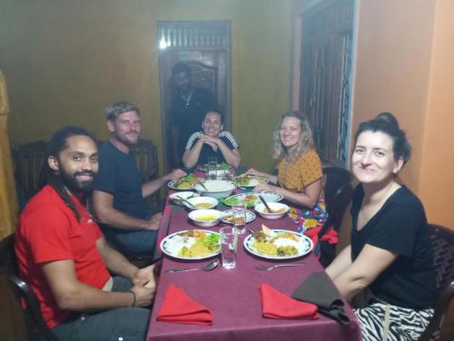a group of people sitting around a table eating food at SIGIRI HUNTER'S HOMESTAY & Hostel in Sigiriya