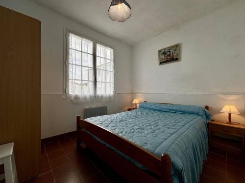 une chambre avec un lit avec une couette bleue et une fenêtre dans l'établissement Mais 4 pièces Oléron 6 couchages SAINT DENIS D'OLERON SDO000-162, à Saint-Denis-dʼOléron
