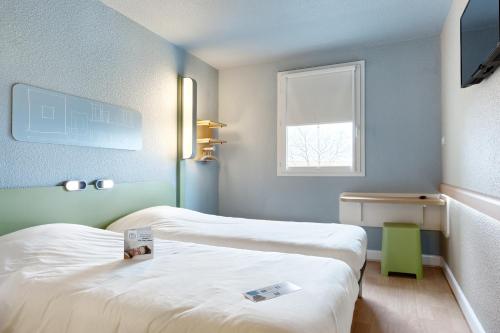 a hotel room with two beds and a window at ibis budget La Roche Sur Yon Vendespace in Mouilleron-le-Captif