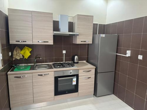 a small kitchen with a refrigerator and a sink at Appartement Somone , Sall Residence in Mbour