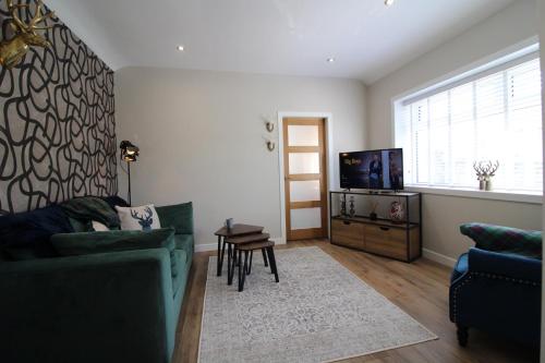 a living room with a green couch and a television at Links Cottage, Prestwick in Prestwick