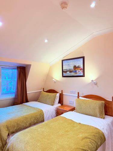 a room with two beds and a tv on the wall at Europa House Hotel, London Paddington in London