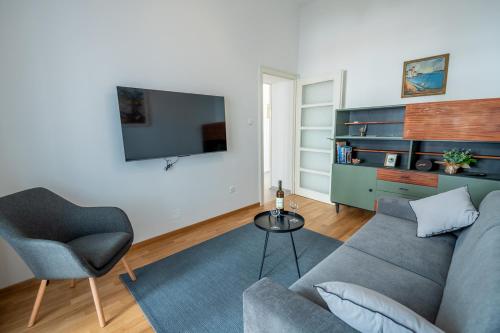 a living room with a couch and a chair and a television at Eta - apartman u centru grada in Pula