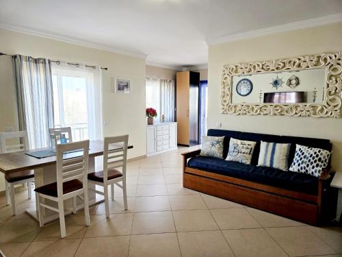 a living room with a couch and a table and chairs at Penthouse Cabanas Sun - Algarve in Cabanas de Tavira