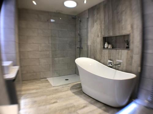 a large white tub in a bathroom with a shower at Luxury Cosy Cottage in Criccieth