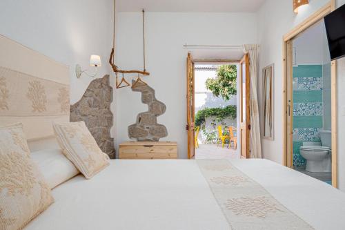 une chambre avec un lit blanc et une salle de bain dans l'établissement Nott'e Die, à Olbia