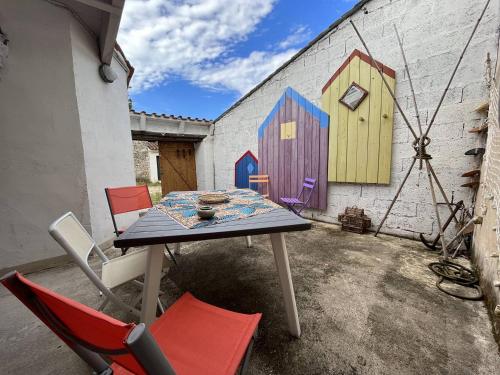 une table avec des chaises et une peinture murale dans l'établissement Mais 4 pièces Oléron 6 couchages SAINT GEORGES D'OLERON SGO000-607, à Saint-Georges-dʼOléron