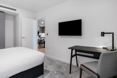 a bedroom with a bed and a desk and a television at CitySuites 2 Aparthotel in Manchester