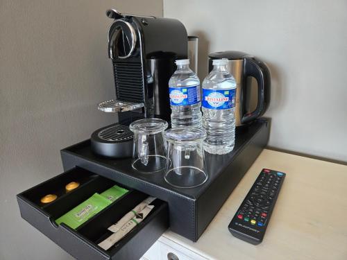 a coffee maker with two bottles of water and a remote control at Hôtel Le SAINT-GENIÈS in Uzès