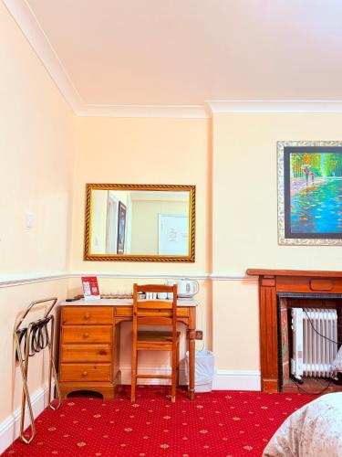a bedroom with a desk with a mirror and a chair at Europa House Hotel, London Paddington in London