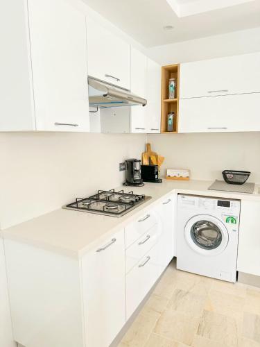 a white kitchen with a stove and a washing machine at Yasmine djerba 2 in Temlale