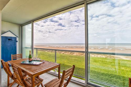 - une salle à manger avec une table et des chaises et une vue sur l'océan dans l'établissement Seafront flat near Cabourg with free private parking, à Varaville