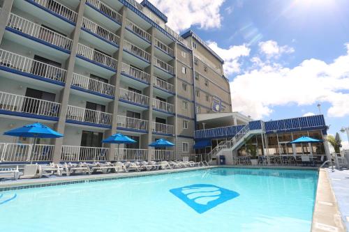 a pool in front of a hotel with chairs and umbrellas at Adventurer Oceanfront Inn in Wildwood Crest