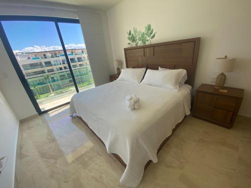 a bedroom with a large bed with a teddy bear on it at Depa boutique nuevo de 2 recámaras - diseño, confort y excelente ubicación con alberca in Playa del Carmen