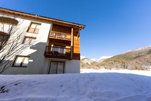 a building with a balcony in the snow at Bel appartement 6pers lumineux - Arvieux - Parc naturel du Queyras in Arvieux