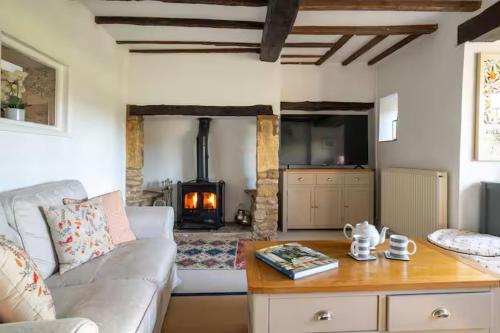 a living room with a couch and a table with a fireplace at Pass the Keys Delightful 4 bedroom Cotswold character cottage in Cheltenham