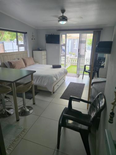 a bedroom with a bed and a table and chairs at Hartenbos Breakaway - LightHouse Cottage in Mossel Bay