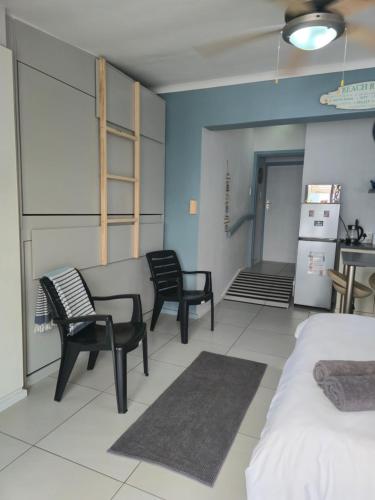 a room with two chairs and a table and a refrigerator at Hartenbos Breakaway - LightHouse Cottage in Mossel Bay