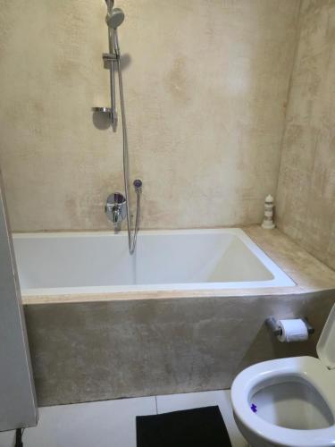 a bathroom with a bath tub and a toilet at Hartenbos Breakaway - LightHouse Cottage in Mossel Bay