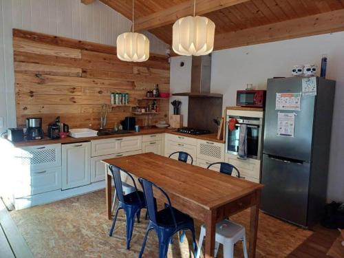 une cuisine avec une table en bois et un réfrigérateur dans l'établissement La forestière avec Jacuzzi pour 6 personnes, à Saint-Georges-dʼOléron