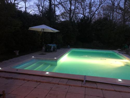 une piscine avec un parasol à côté d'une table et un parasol dans l'établissement Villa with pool in Private Golf Residence, à Saint-Sulpice-et-Cameyrac