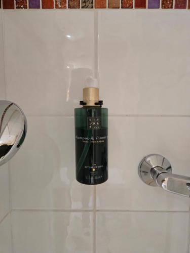 a green bottle of soap sitting on a bathroom sink at Hôtel Le SAINT-GENIÈS in Uzès