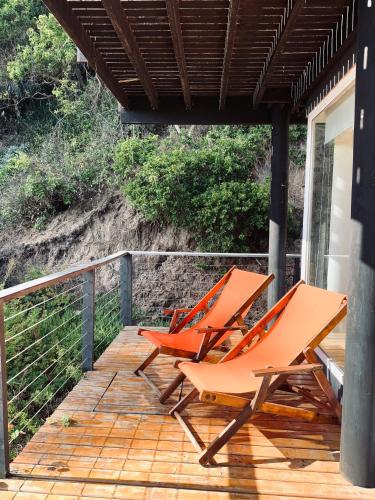 two orange chairs sitting on a wooden deck at Lofts - Casa El Pangue, Zapallar in Zapallar