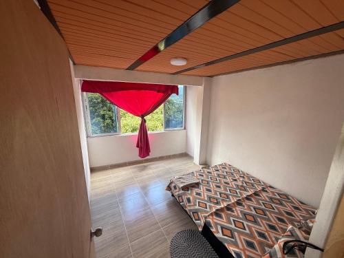 Habitación con cama y ventana con cortina roja. en apartamento campestre 201, en Ibagué