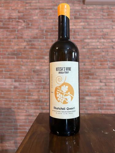 a bottle of wine sitting on a wooden table at Wine tasting - Kitesa's wine cellar in Mtskheta