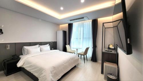 光州Cheomdan Lantana Hotel的一间卧室，里面有一张床、一张桌子和一把椅子