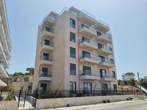 a tall building with a fence in front of it at Calypso Sea View Apartament Saranda in Sarandë
