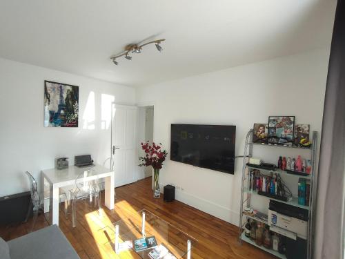 a living room with a television and a table at Bel appartement Paris Ouest sur cour proche métro in Boulogne-Billancourt