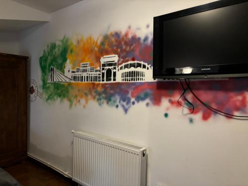a wall with a tv and a painting on a wall at B&B Maria in Bucharest