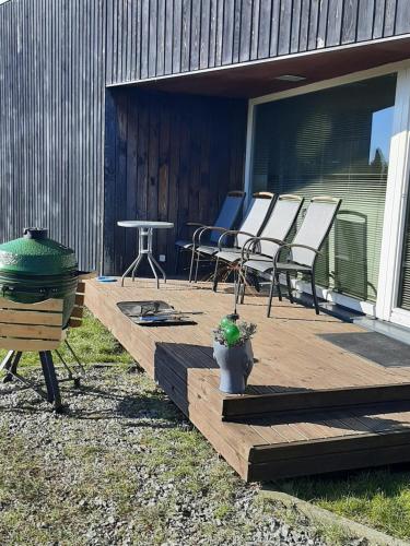 a wooden deck with chairs and a grill on a house at Päikeseline Apartment WITH SAUNA in Kuressaare