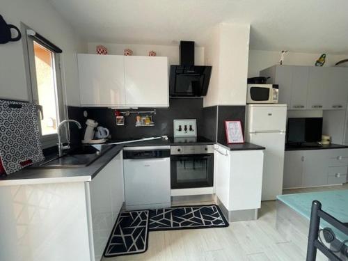 une cuisine avec des armoires blanches et des appareils électroménagers blancs dans l'établissement 108 Quai d'azur H21 CAP D'AGDE, 2 Pièces 4 pers avec parking proche port et môle, au Cap d'Agde