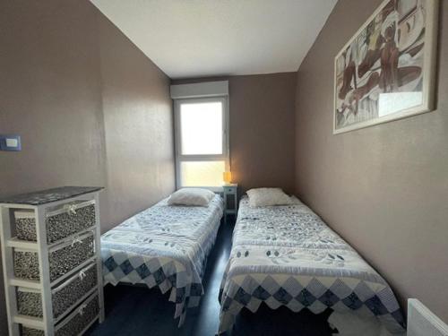 une chambre avec deux lits et une fenêtre dans l'établissement 108 Quai d'azur H21 CAP D'AGDE, 2 Pièces 4 pers avec parking proche port et môle, au Cap d'Agde