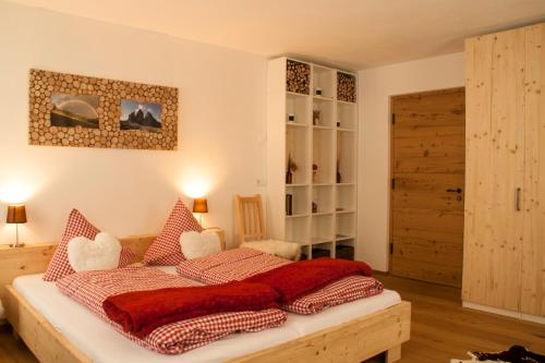 a bedroom with a bed with red pillows on it at Preindlerhof Farmhouse in Santa Maddalena