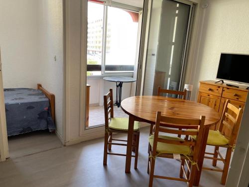 une salle à manger avec une table, des chaises et une télévision dans l'établissement Studio cabine, plage de St Cyprien, 200 m de la mer, à Saint Cyprien Plage
