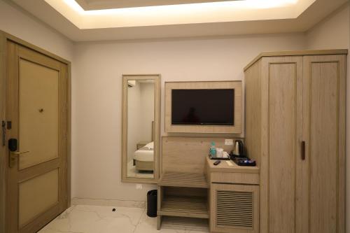 a room with a television and a desk with a mirror at Hampton By IC's in Noida