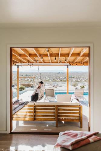 a woman sitting on a bed in a room with a window at Loma Vista By The Cohost Company in Sunfair Heights